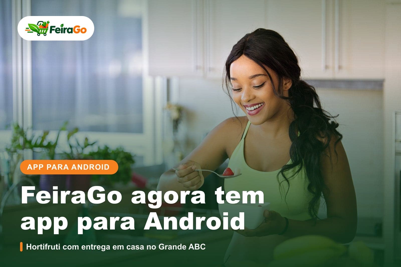 Mulher sorridente na cozinha de casa saboreando uma tigela de frutas