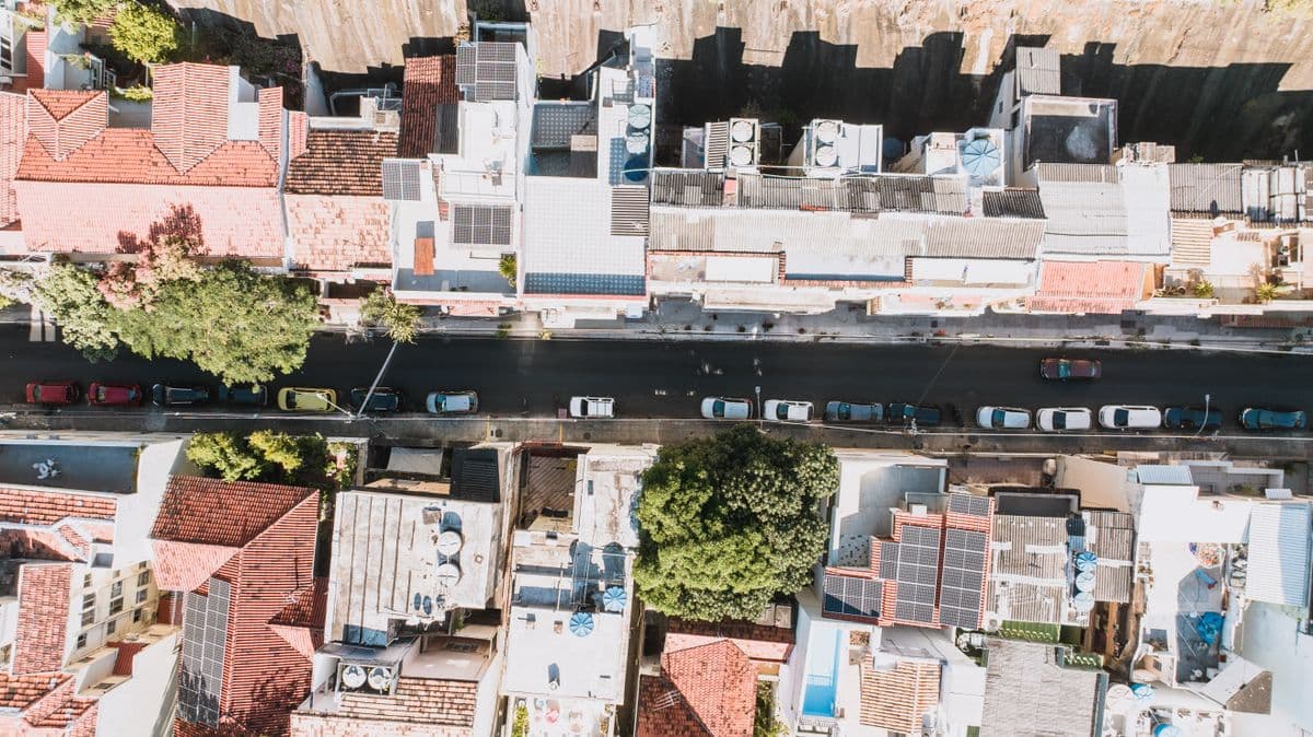 Rua residencial vista de cima, com casas de telhado e carros estacionados