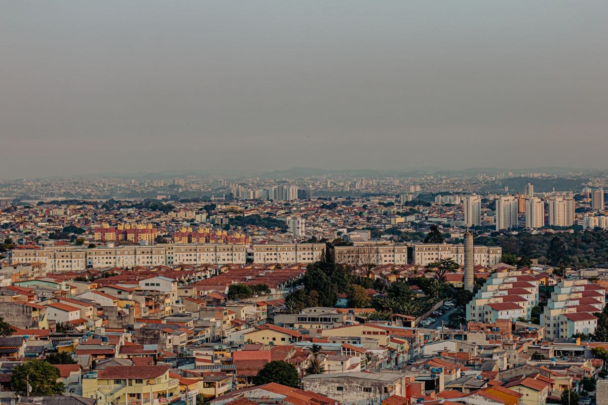 Vista de uma cidade com casas de telhado laranja e prédios ao fundo
