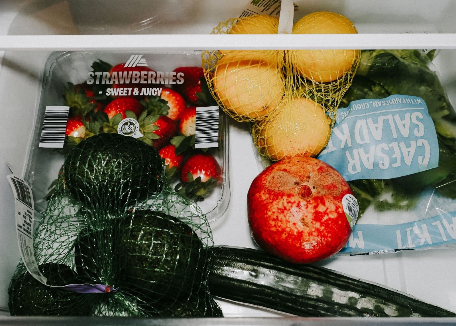 Variedade de frutas e vegetais frescos organizados na gaveta da geladeira