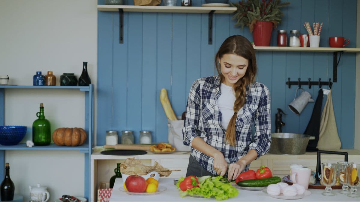 Mulher cortando legumes para uma salada em uma cozinha