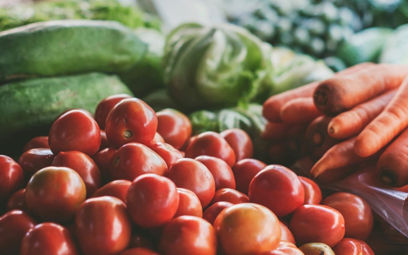 Tomates vermelhos e cenouras empilhados em uma banca de feira