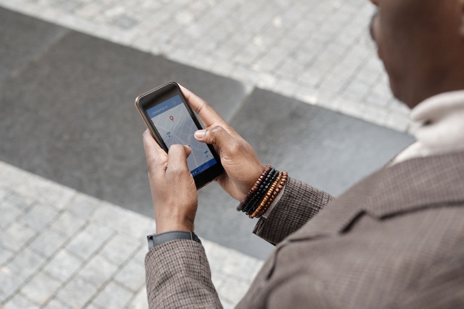 Mãos segurando um celular com um mapa e um marcador de localização na tela