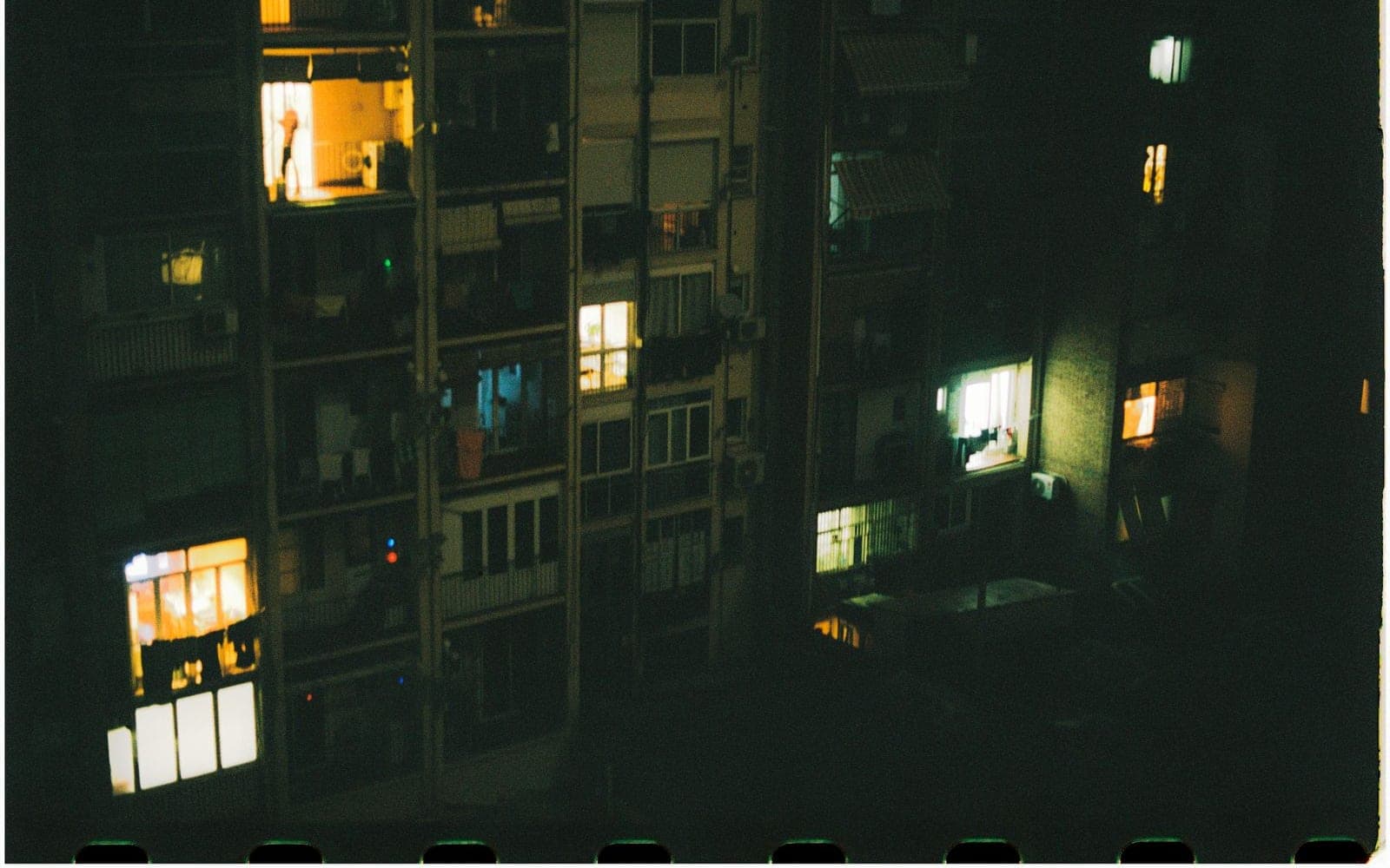 Fachada de prédio à noite com janelas iluminadas em amarelo