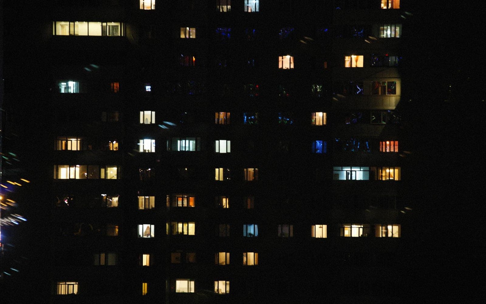 Prédio de apartamentos à noite com dezenas de janelas acesas