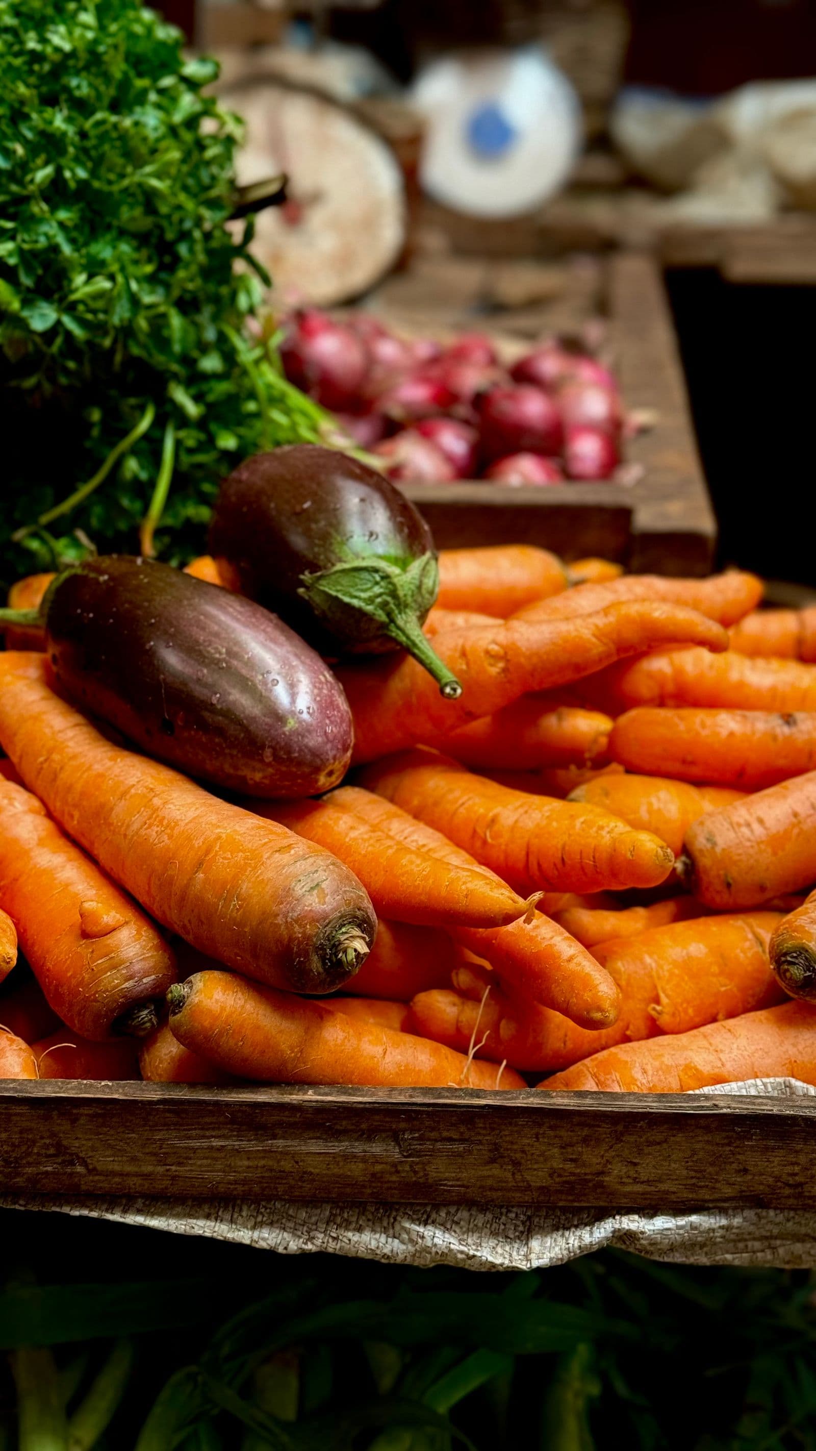 Cenouras, berinjelas e outras verduras frescas numa caixa de feira