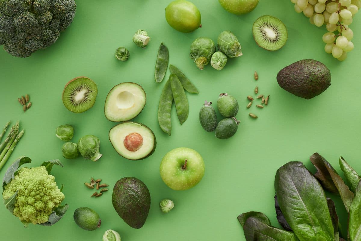 Brócolis, ervilhas-torta, couve-de-bruxelas e outros vegetais verdes dispostos sobre fundo verde