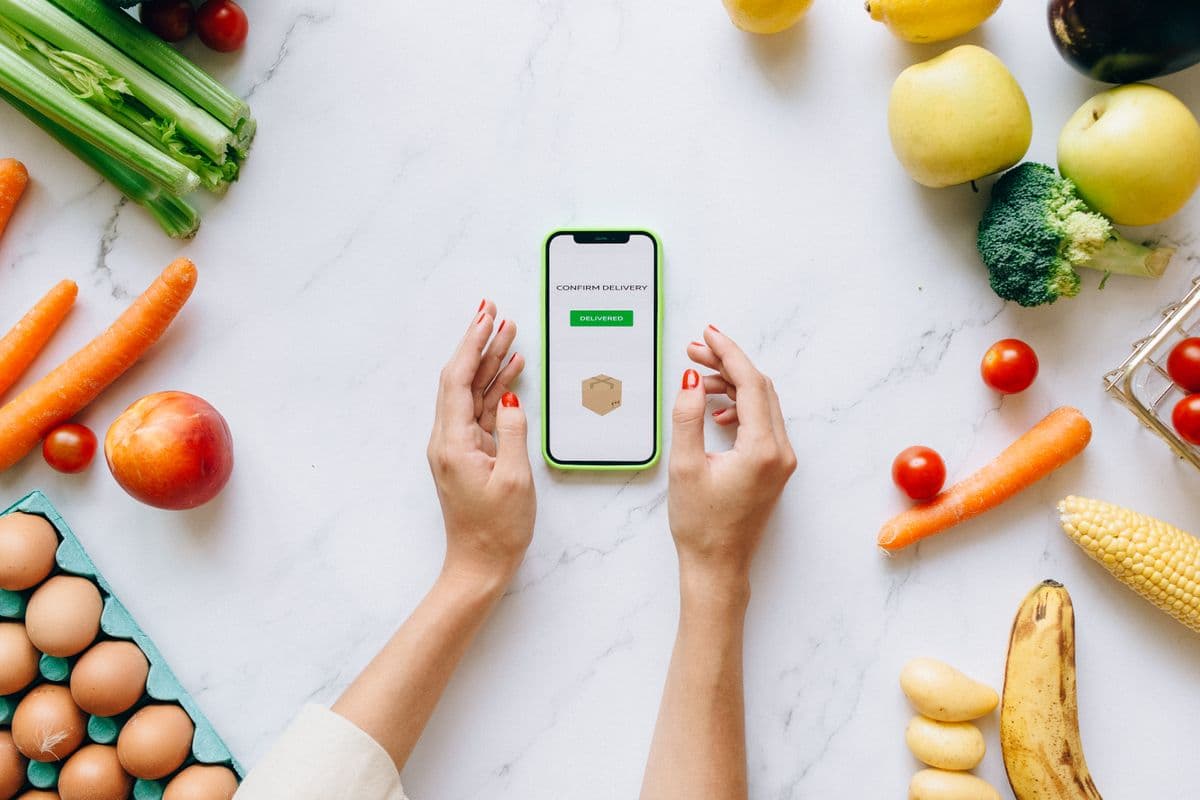 Frutas, verduras e ovos ao redor de um celular mostrando a confirmação de um pedido
