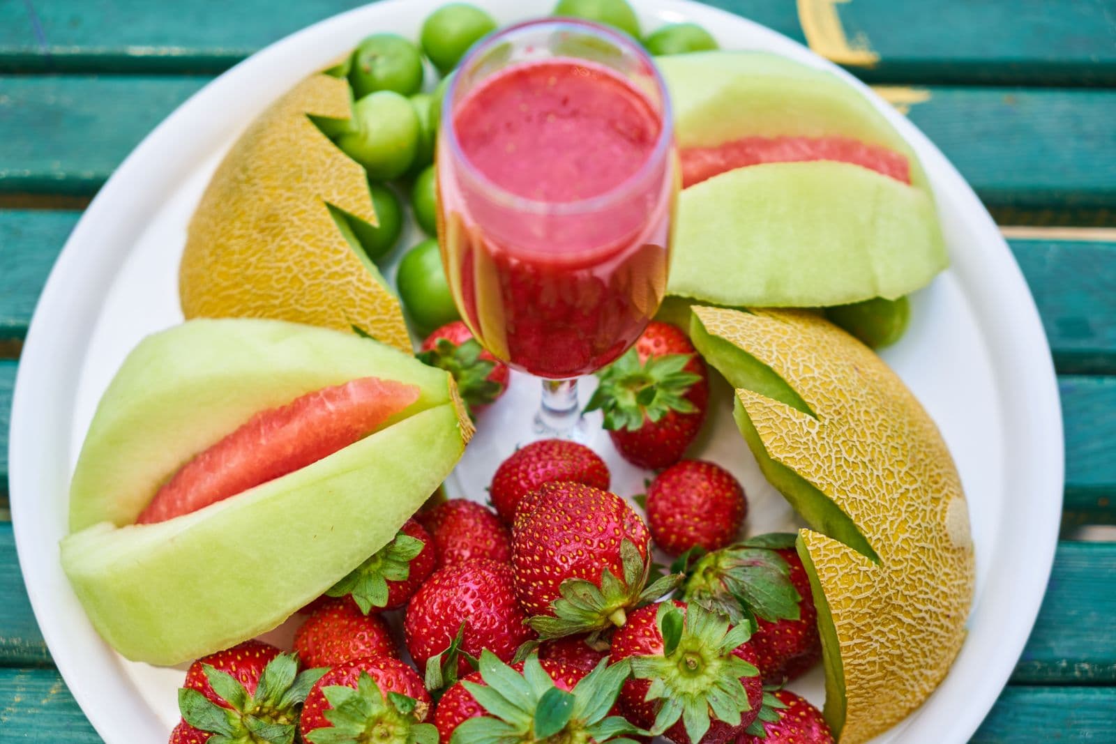 Prato com melão, morangos e suco de fruta vermelho