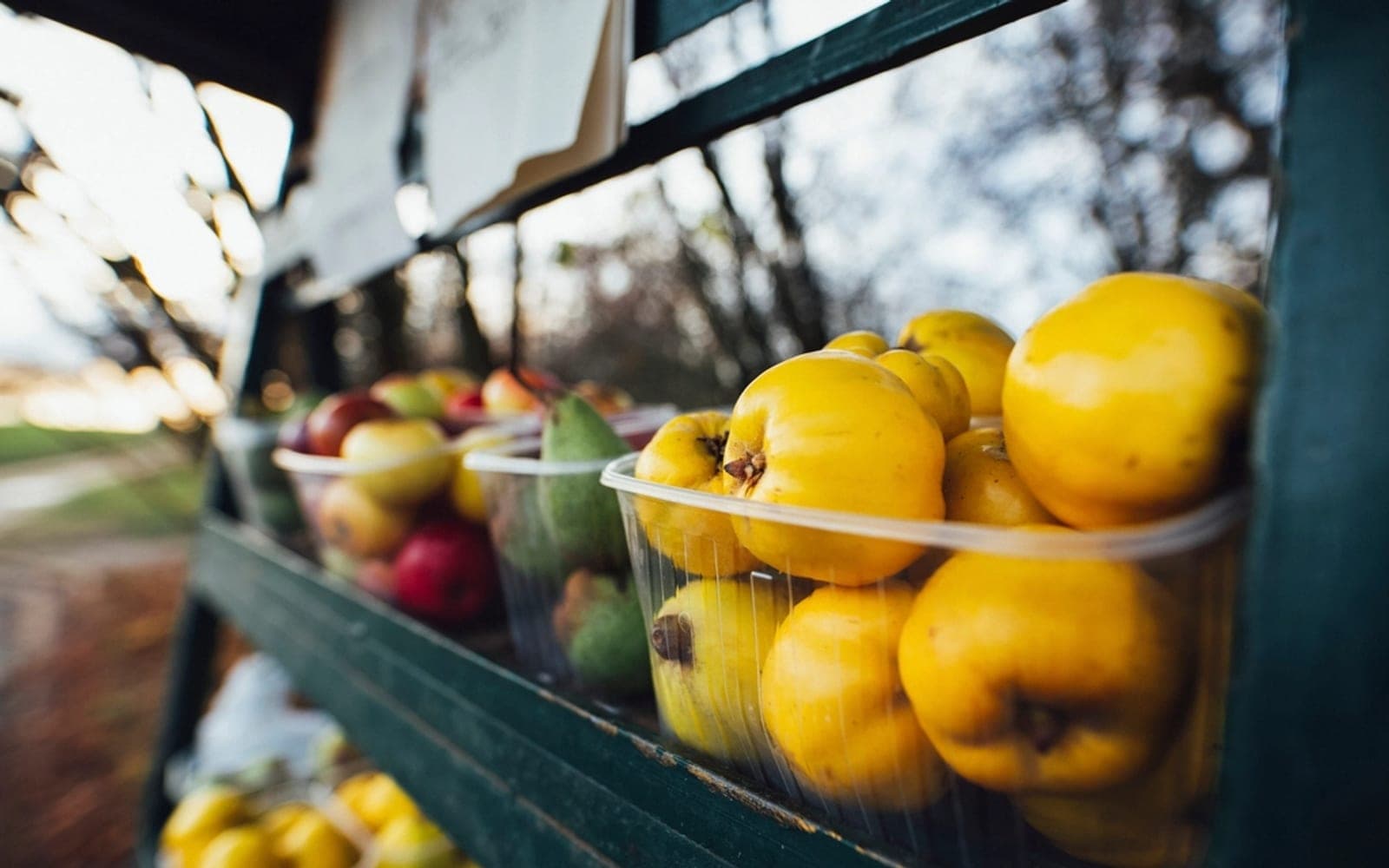 Frutas amarelas e maçãs em cestos de plástico em uma banca