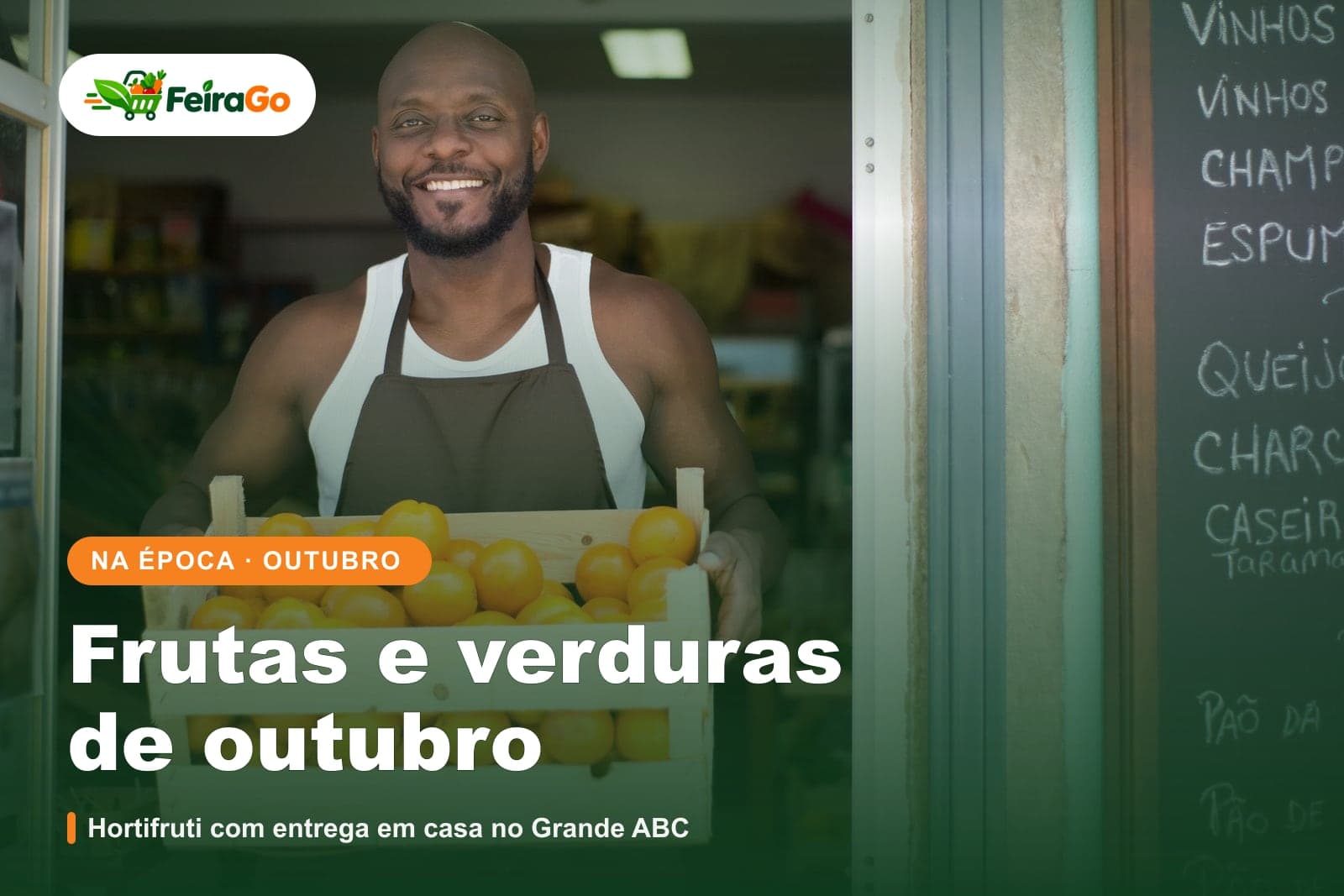 Homem sorridente de avental marrom segurando uma caixa de madeira cheia de laranjas na porta de uma loja