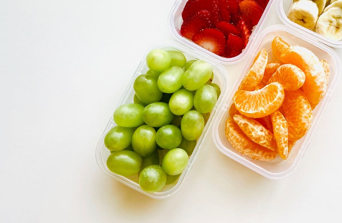 Potes com uvas verdes, gomos de tangerina, morangos fatiados e banana