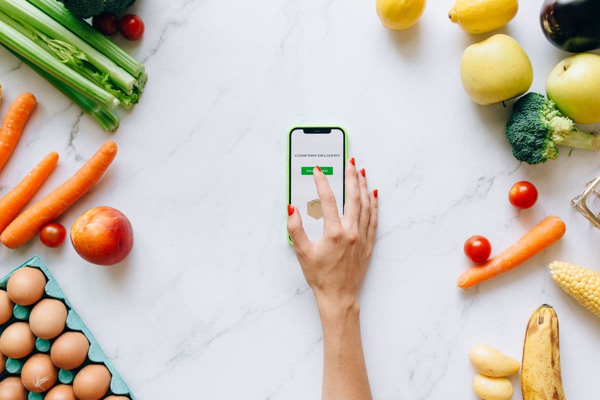 Frutas, verduras e ovos ao redor de um celular mostrando a confirmação de um pedido