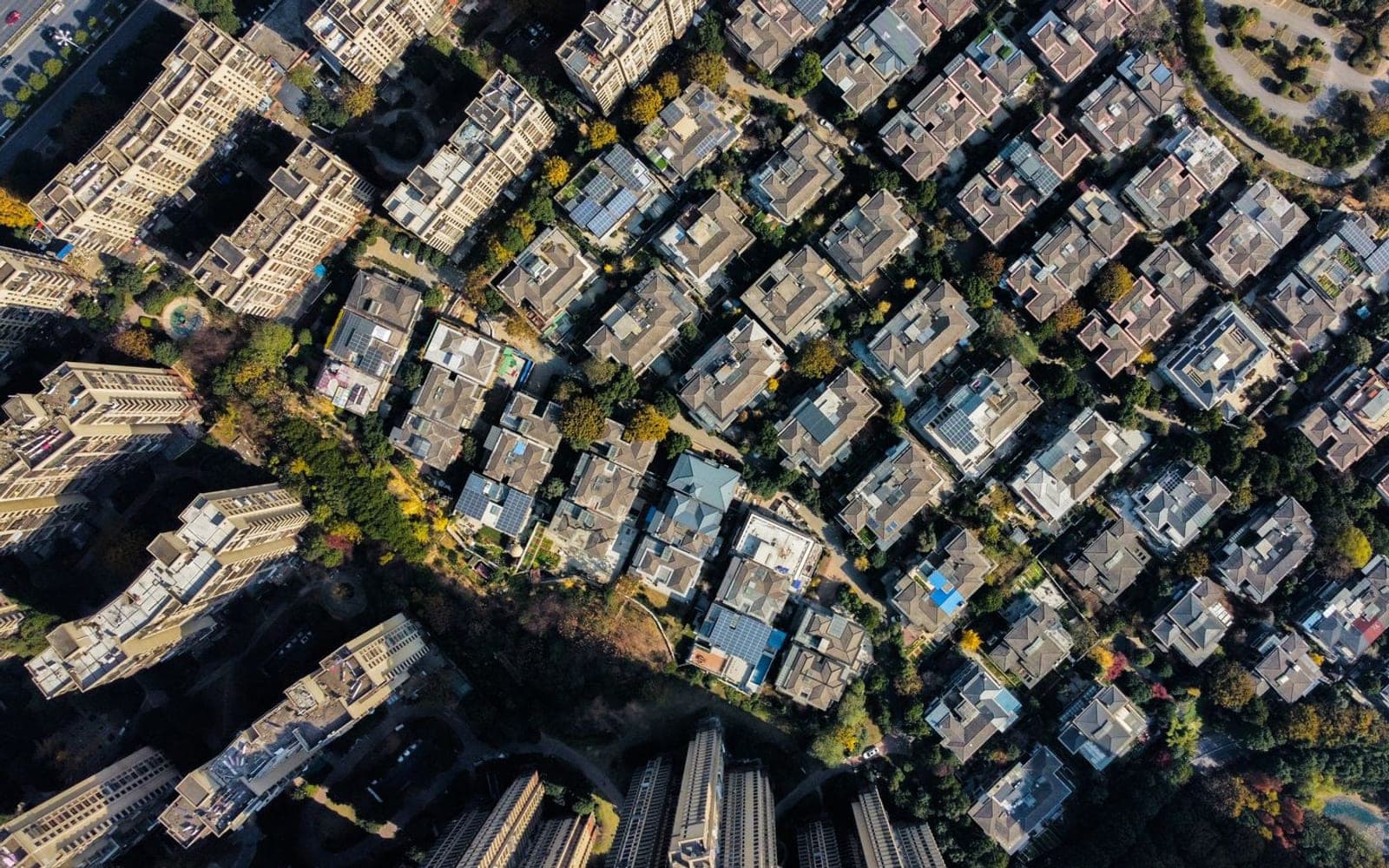 Vista de cima de um bairro residencial denso, com prédios e árvores entre as ruas