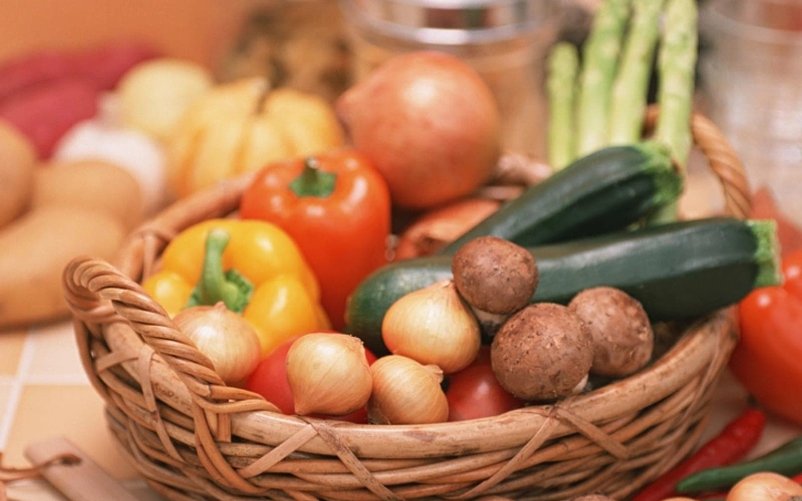 Cesta de palha com pimentões, abobrinha, cebolas e cogumelos