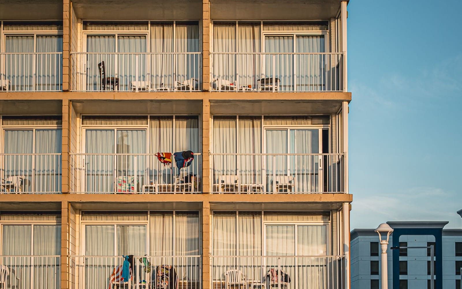Fachada de prédio residencial de tijolinhos com varandas e céu azul ao fundo