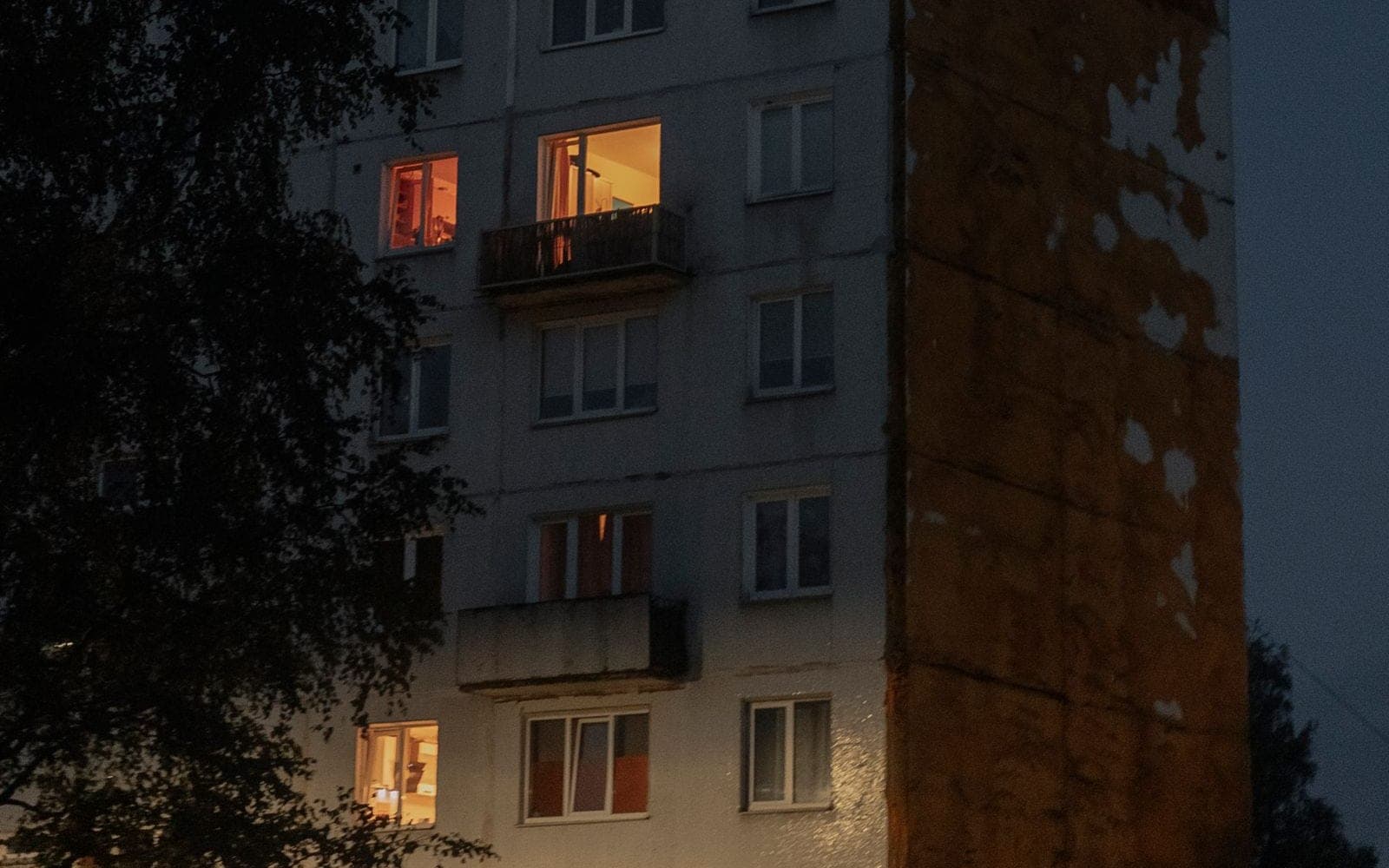 Edifício residencial de concreto ao entardecer, com janelas acesas
