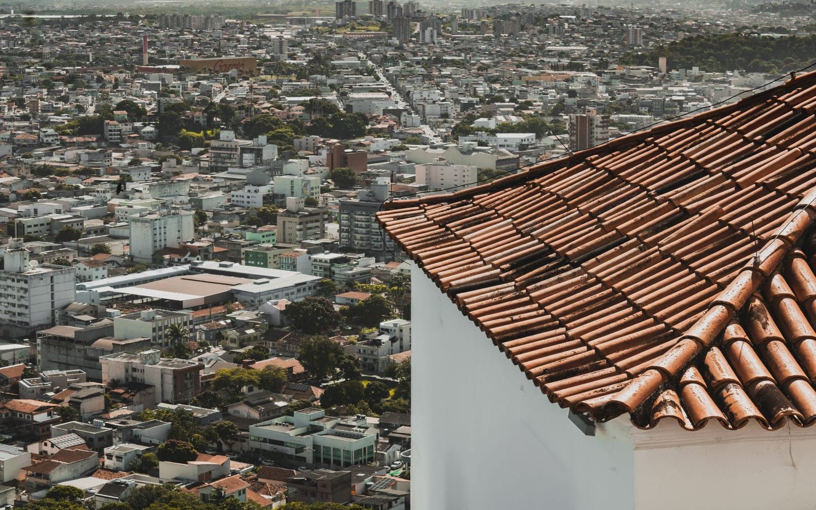 Vista aérea de uma cidade brasileira, com um telhado de cerâmica em primeiro plano