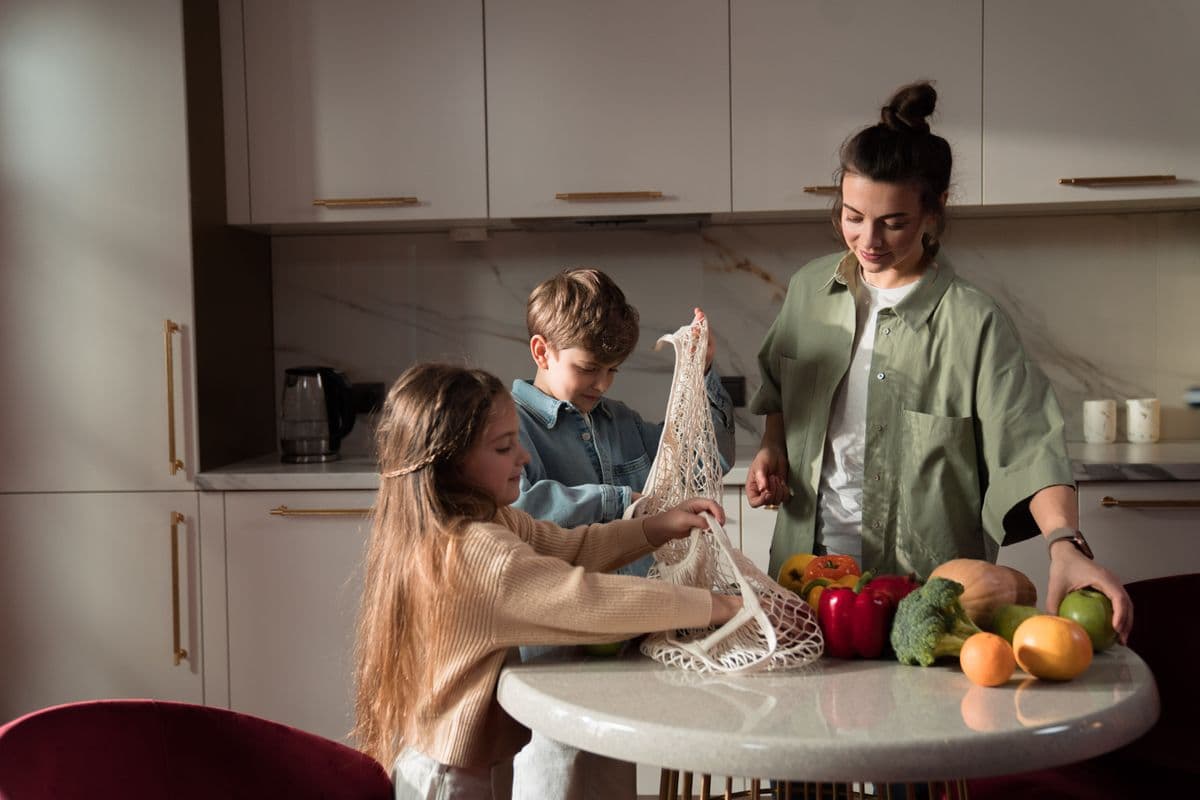 Família escolhendo cenouras, pimentões e brócolis na bancada da cozinha