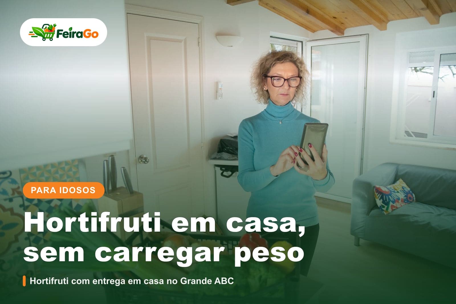 Senhora de óculos de pé numa cozinha com uma cesta de verduras, segurando o celular