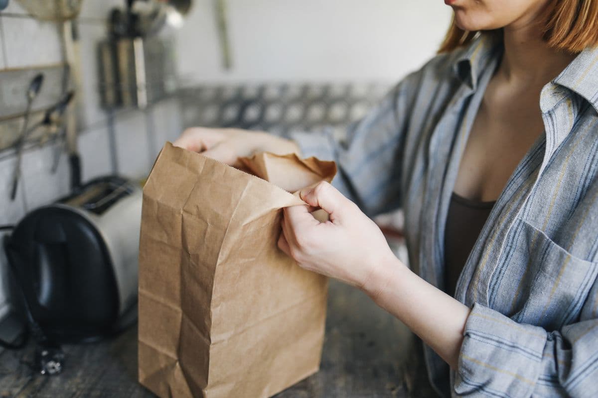 Mulher abrindo uma sacola de papel na cozinha