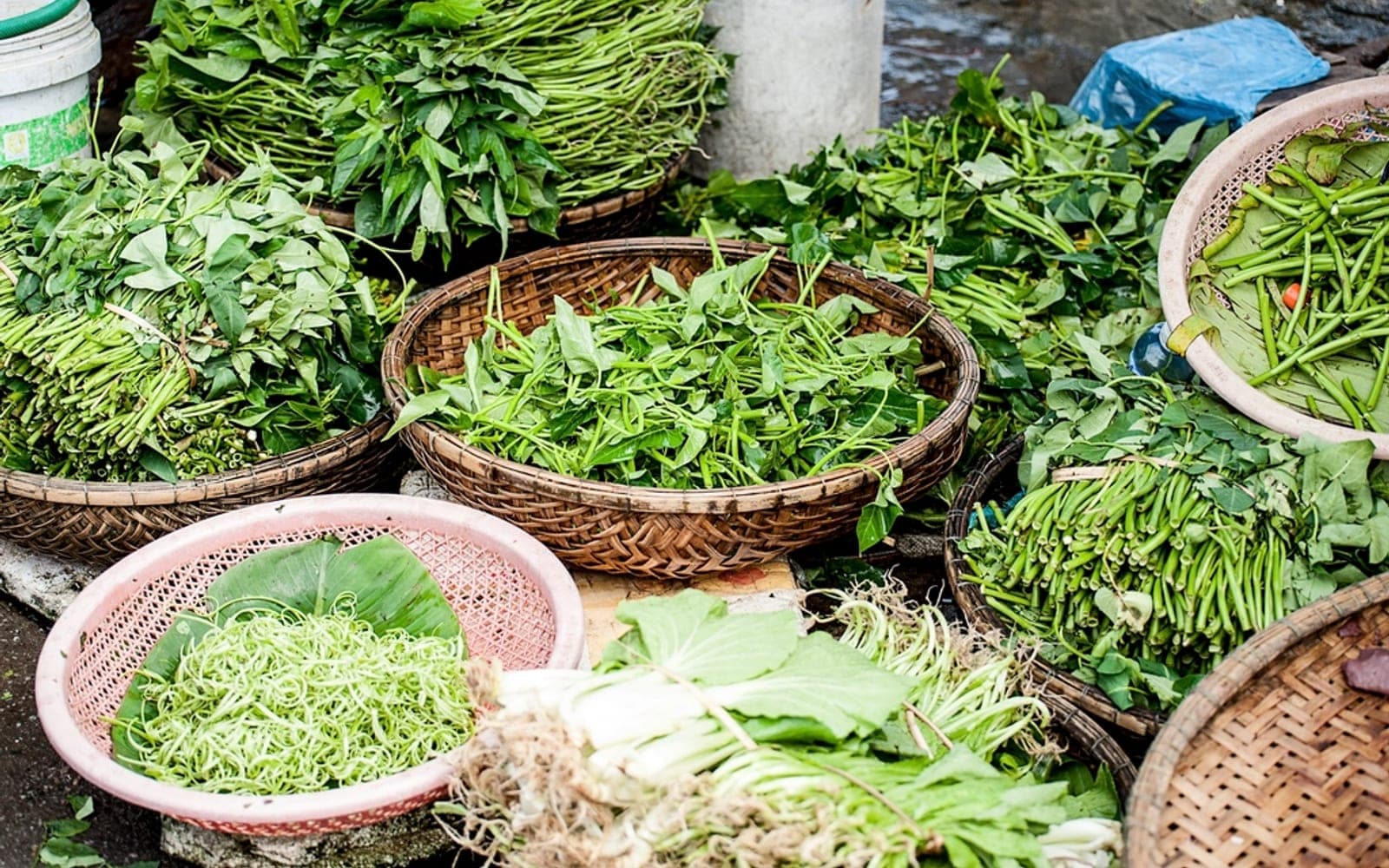 Cestos de palha com folhas verdes variadas em uma banca