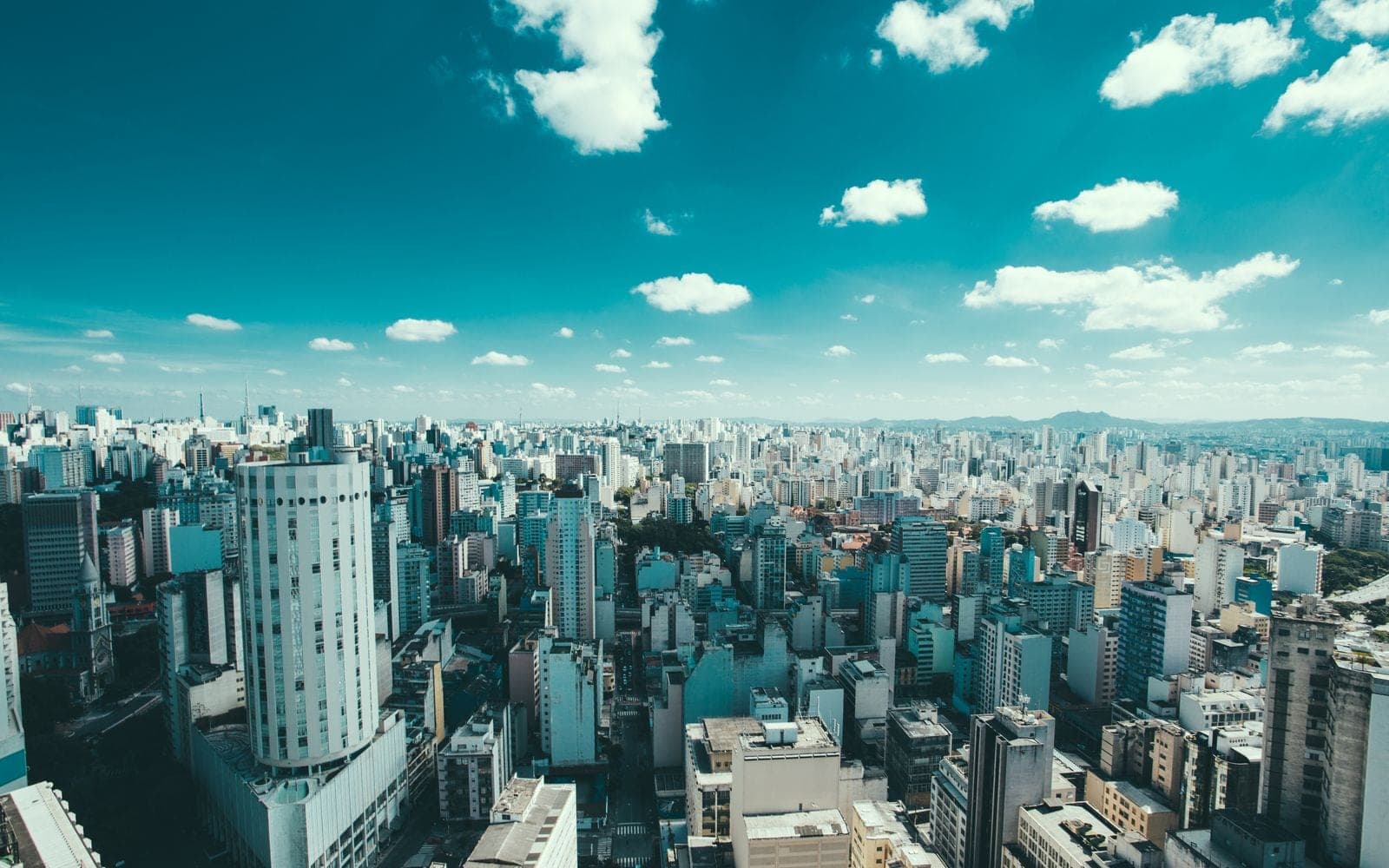Vista panorâmica de uma grande cidade com prédios e céu azul com nuvens