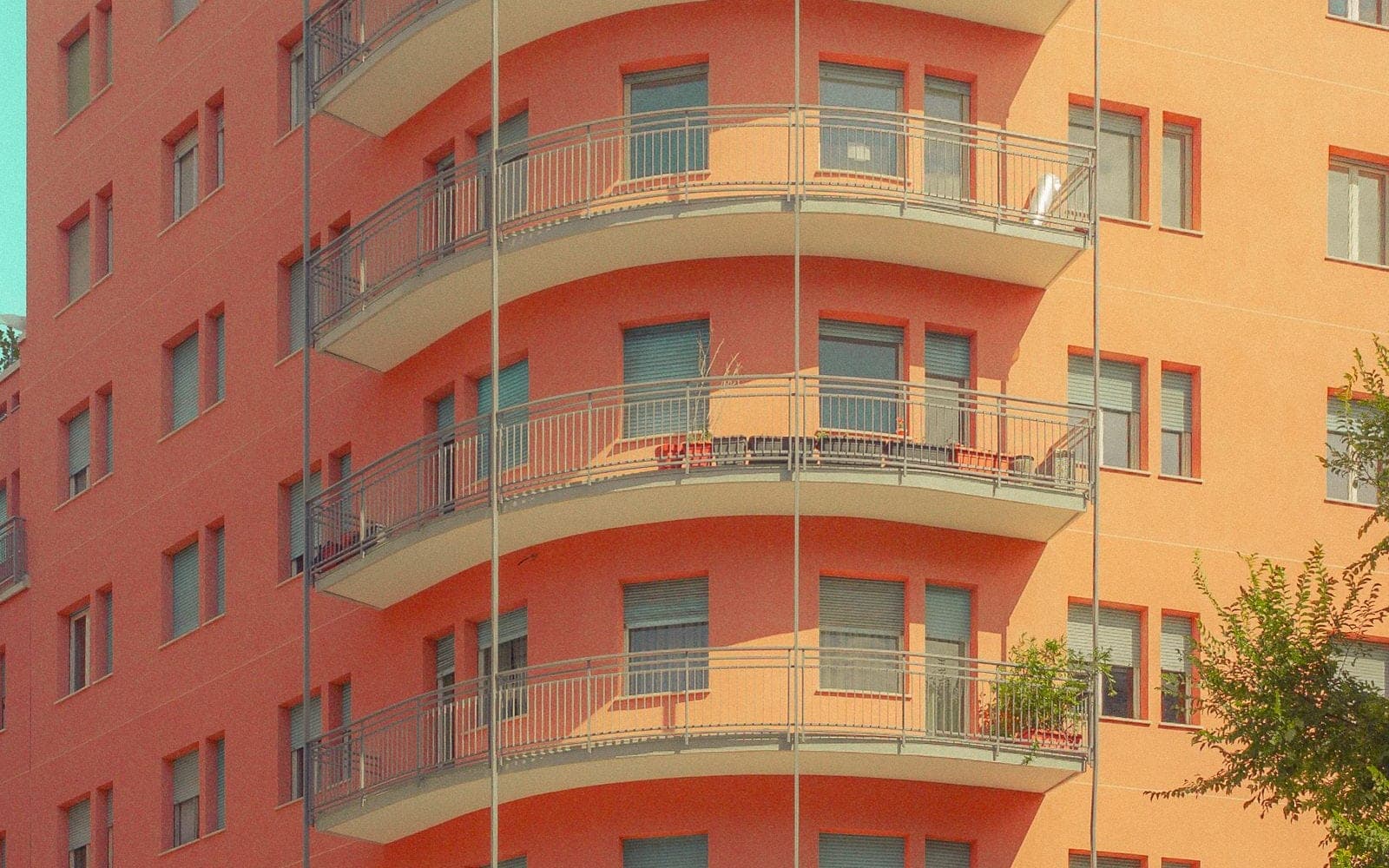 Prédio residencial laranja com varandas curvas contra um céu azul
