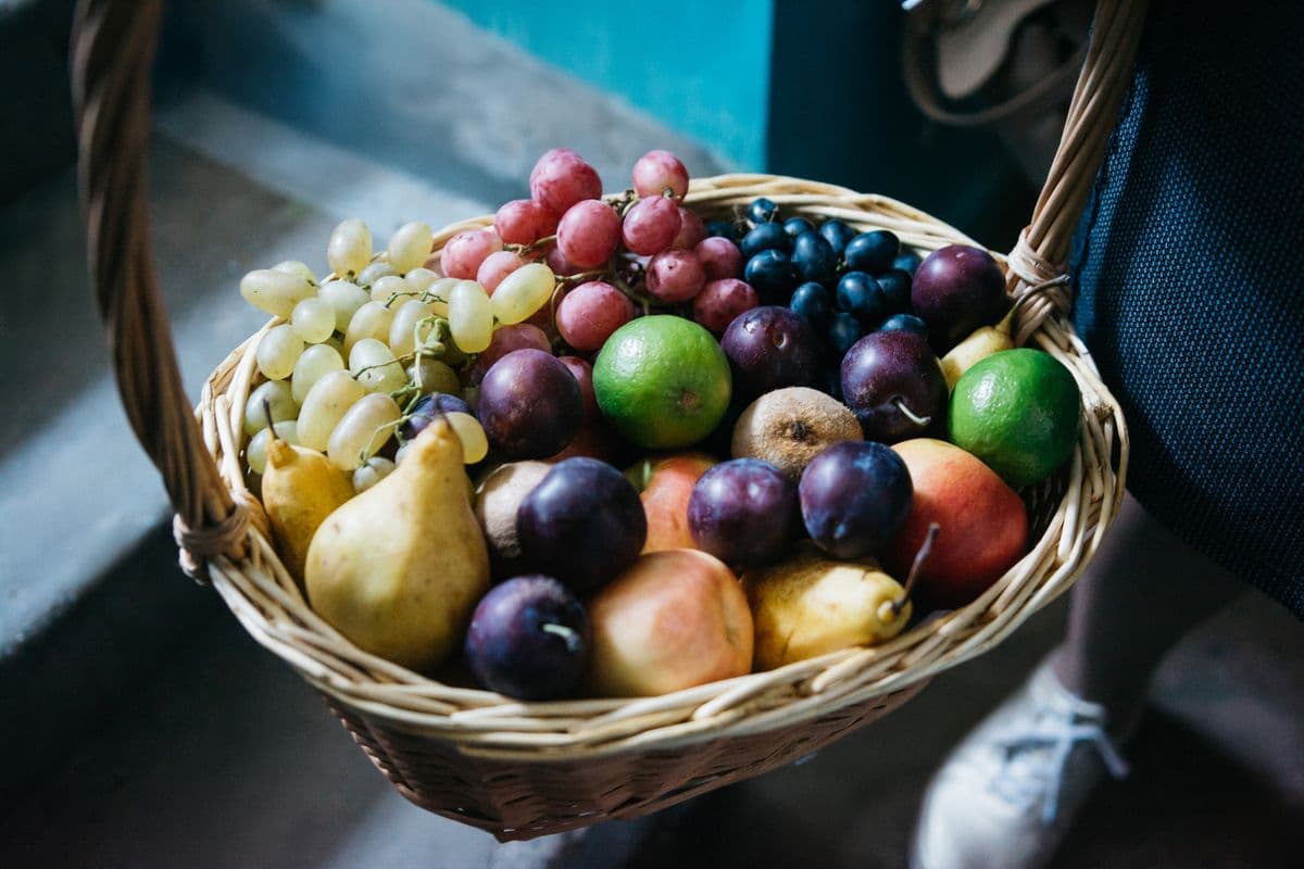 Cesta de frutas variadas com uvas, limões e peras