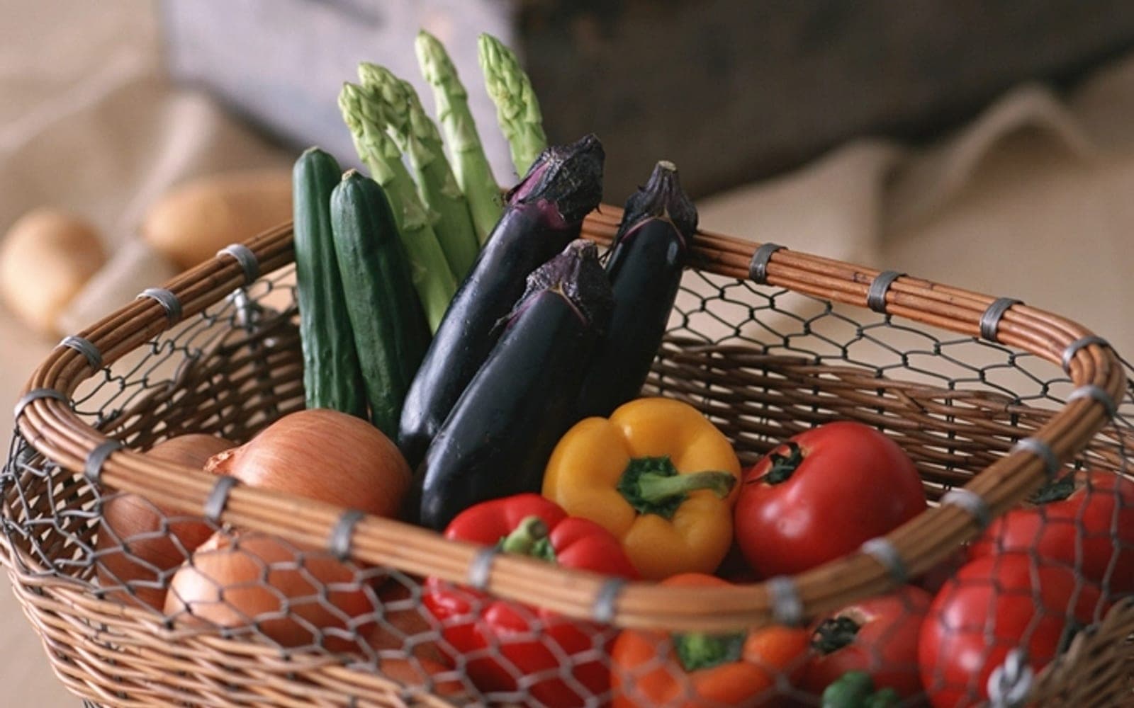 Cesta de vime com aspargos, berinjela, pimentões e tomates