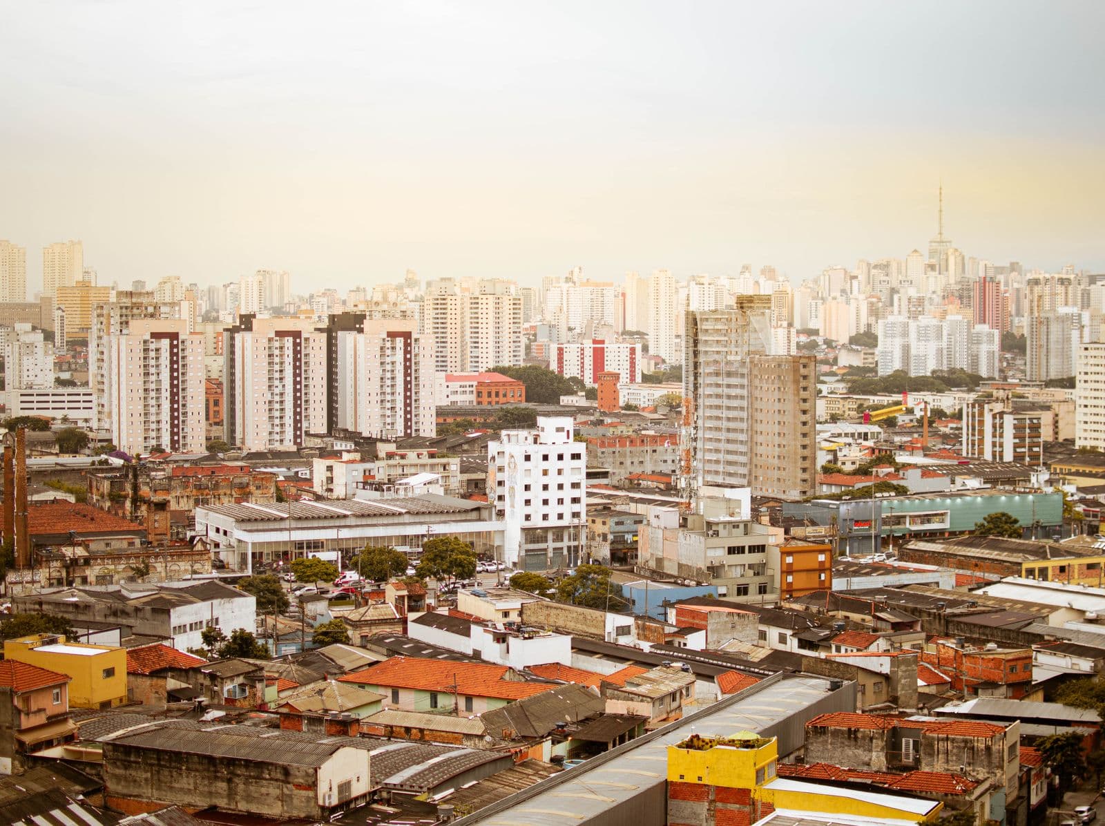 Vista ampla de uma cidade com prédios residenciais, casas de telhado e galpões