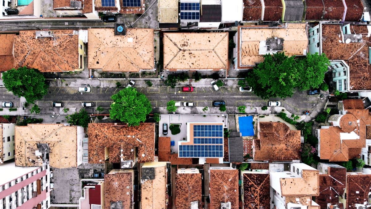 Bairro residencial visto de cima, com telhados, árvores e uma rua com carros