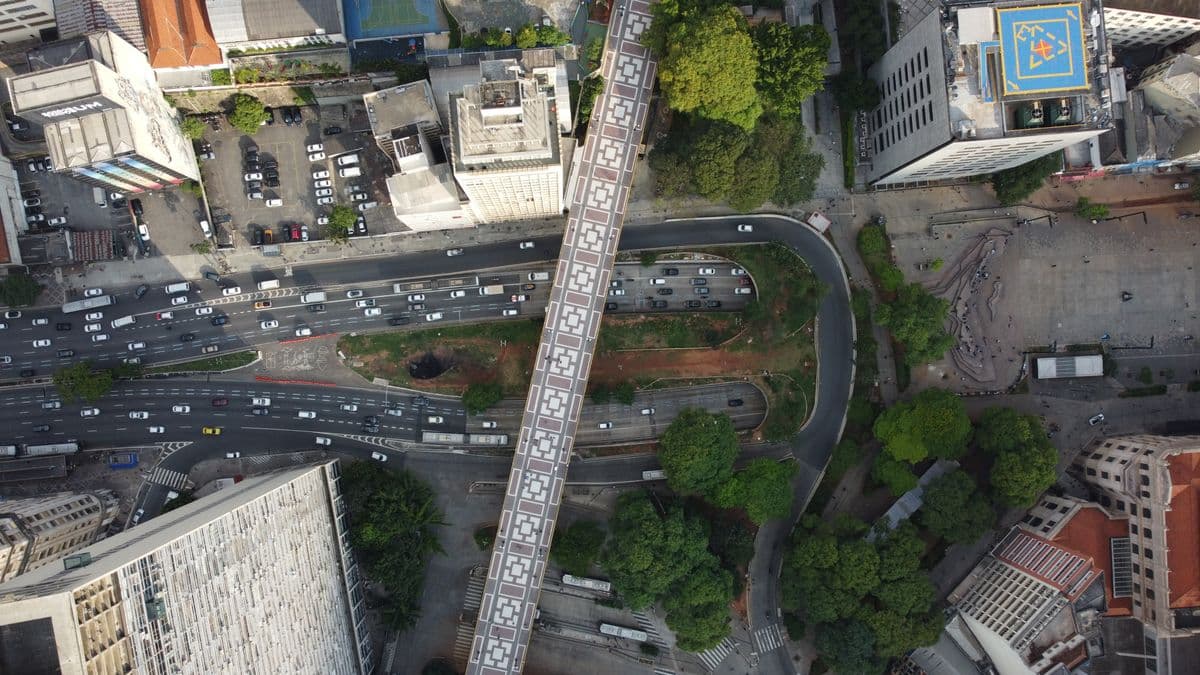 Avenida movimentada vista de cima, com viaduto e prédios ao redor