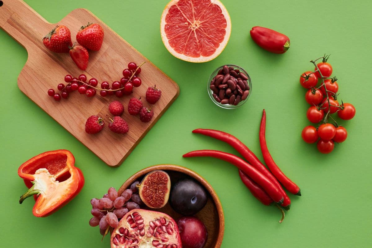 Morangos, framboesas, pimentões, tomates e romã sobre fundo verde
