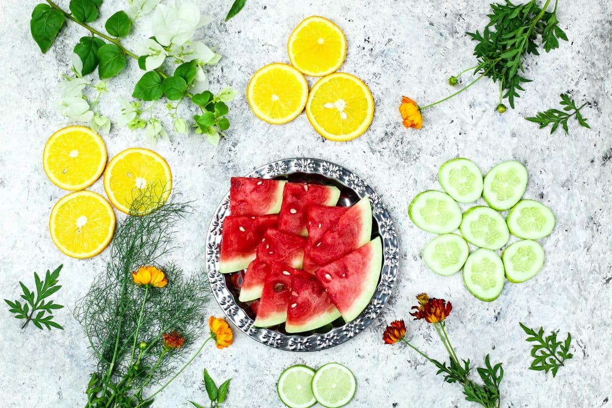 Fatias de melancia, laranja e pepino dispostas sobre uma superfície clara