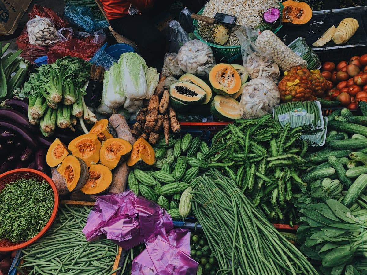 Banca com abóboras cortadas, mamão, vagem, pepino, acelga e outros legumes