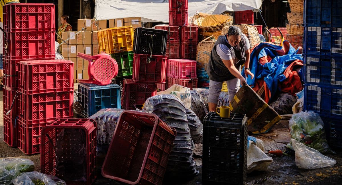 Pessoa organizando caixas coloridas de produtos em um mercado ao ar livre